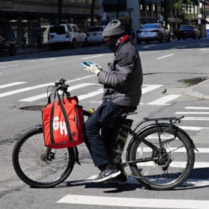 A Grubhub delivery person checks his phone during the coronavirus pandemic on May 3, 2020 in New York City.